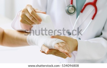 Close-up of female doctor with stethoscope bandaging hand of patient. (Selective Focus)