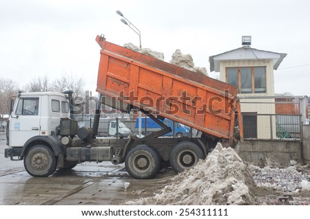 MOSCOW, RUSSIA - February 13, 2015: Unloading dirty snow from the back of the orange dump truck, Moscow