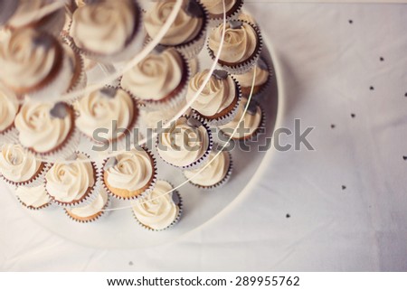 A vintage clear cake stand full of butter cream cup cakes. Vintage color/colour filter added. Shot at angle from above.