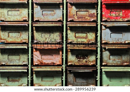 a row of old rusty metal filing cabinets with coloured/colored peeling paint. Four across and four down filling frame.