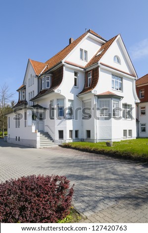 A grand three storey villa with a front yard in front of blue sky