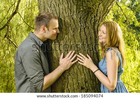 A young couple is romantic in the park on a lake on the go. They face each other on a tree trunk so in love with his eyes.