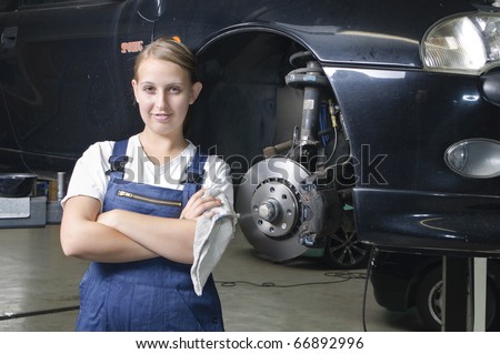 Young woman in work clothes, Apprentice is next to a car and is proud and happy in a garage