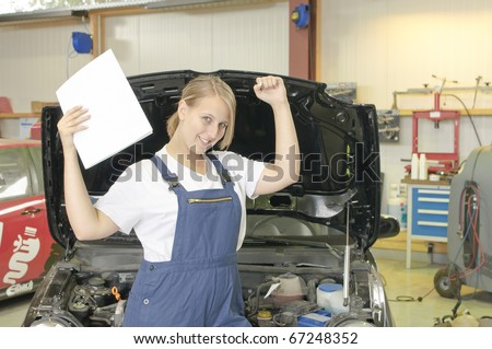 Female apprentice to mechanic has passed the exam and is happy in the Workshop front of a car