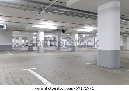 An empty, newly built underground car park in a gray concrete.