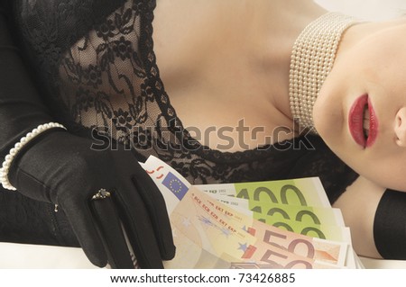 Young pretty woman with blonde hair holding a bundle of banknotes seductive in her hand, against a white background.