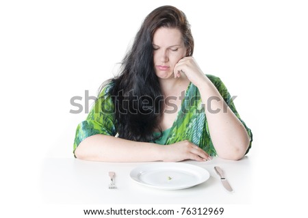 Obese woman with black hair sitting in front of a plate with a single green pea, she looks frustrated in the camera, against a white background.