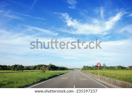 asphalt road through the green field and clouds on blue sky in summer day,which limit speed is 50 , Taiwan