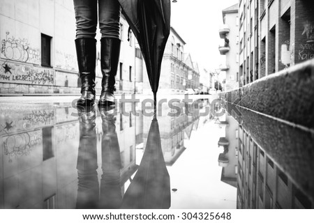 Woman standing in the puddle with umbrella