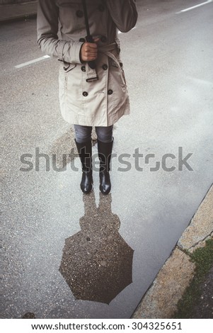 Woman talking on the phone under umbrella in rain