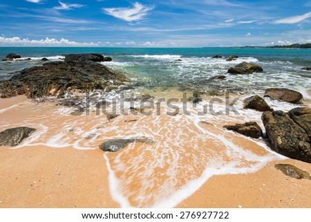 sea waves lash line impact rock on the beach under blue sky, phangnga, thailand