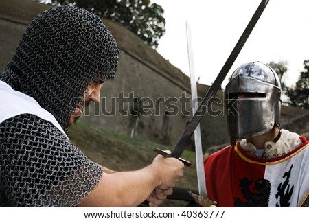 Fight of two knights, angry face on one who strikes other knight with a sword