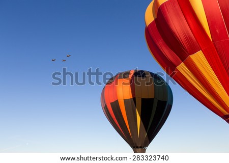 Three Vintage airplanes fly by two hot air balloons to kick off a balloon festival.