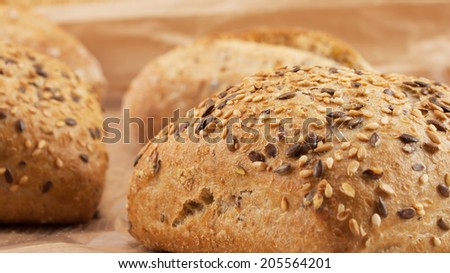 Fresh whole meal bread with seeds on wooden background and wheat