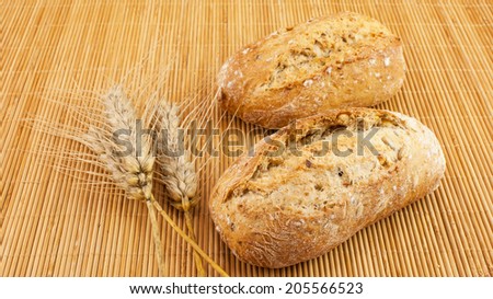 Freshly baked bread with seeds on wooden background and wheat