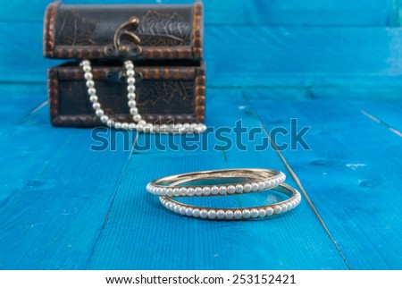 Pearl bracelet and vintage box with jewelry on blue vintage wooden background