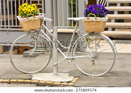 Vintage bicycle with baskets with flowers in front of the office entrance. Office entrance decoration idea