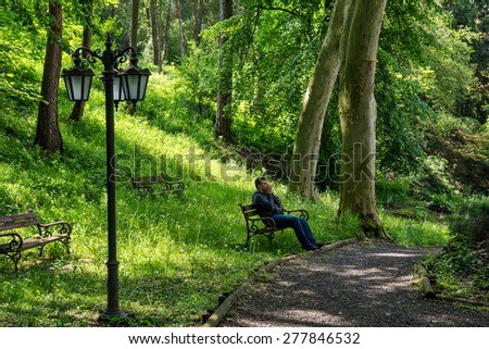 Young man sitting alone on a bench in a park. Concept for grief or sadness