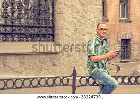 Happy smiling young gypsy man with elegant eyeglasses holding a tablet computer and looking at the camera