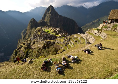 MACHU PICCHU, CUSCO, PERU - AUGUST 2: Group of tourists resting after a mountain hike to pre-Columbian 15th-century Inca site of Machu Picchu on August 2, 2011 in Cusco region, Peru.