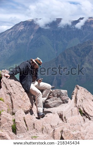 Tourist sends status in social networks, sitting over the Canyon of the Colca River in southern Peru. Peru\'s third most-visited tourist destination with about 160,000 visitors annually