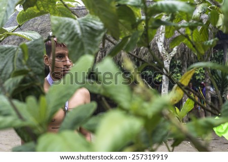 SANTO DOMINGO, ECUADOR - JANUARY 26, 2015: Indian man Colorados tribe in national clothes looks at the tourists through the green jungle, on January 26, 2015 in Santo Domingo, Los Rios, Ecuador