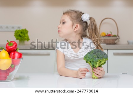 Little cute preschool girl in the kitchen refuses to eat broccoli