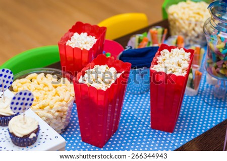 Kids birthday party table with a lot of appetizers, sweets, jelly worms, corn flakes