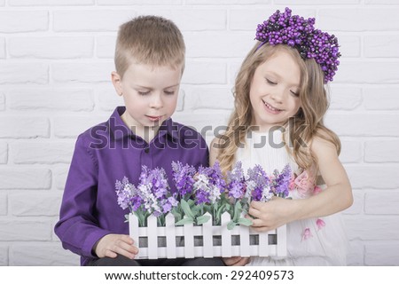 Beautiful pretty smiling kids are playing with flowers in fence pot