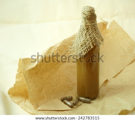bottle with healthy tincture and herbal pills  over old paper background.