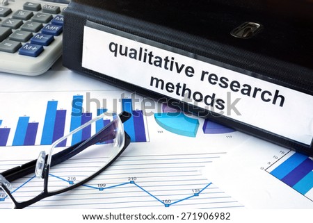 File folder with words words qualitative research methods and financial graphs. Business concept
