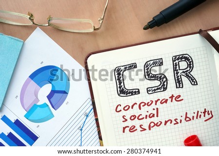 Notepad with words CSR corporate social responsibility concept and marker.