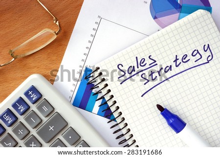 Notepad with  Sales  strategy concept on a wood board.