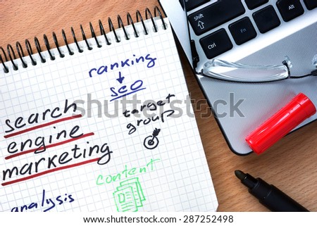 Notepad with words search engine marketing on a wooden background
