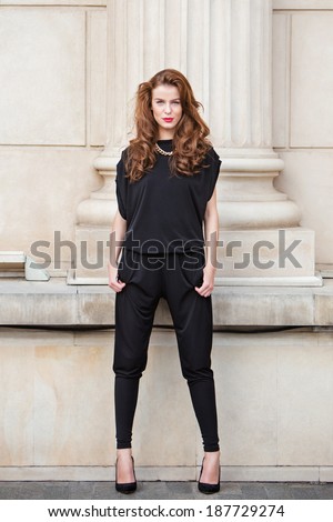 Street fashion. Beautiful young woman wearing backless jumpsuit. Fashion photos.