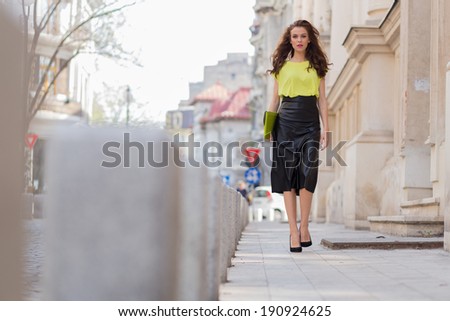 City chic young woman wearing a neon blouse and black leather skirt.
