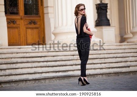 Street fashion. Beautiful young woman wearing backless jumpsuit. Urban fashion.