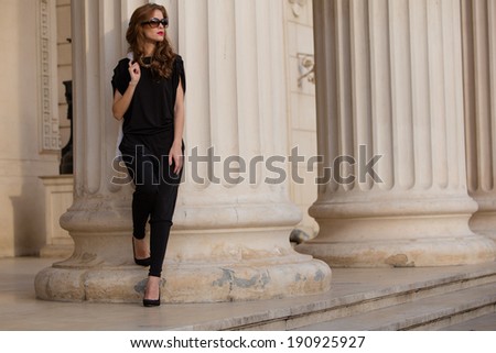 Street fashion. Beautiful young woman wearing backless jumpsuit. Urban fashion.
