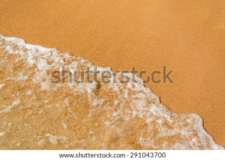 Sea waves roll on yellow fine sand while on vacation