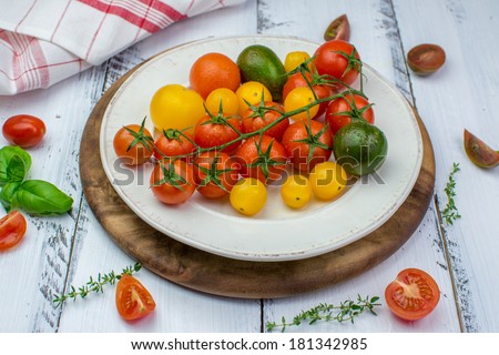 Freshly washed yellow, red, green and black tomatoes on a vintage plate on a white painted shabby wooden surface