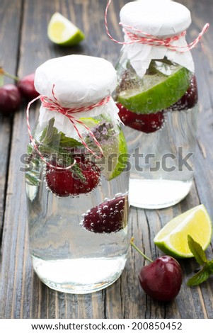 Refreshing lemonade on ice made of lime, mint, thyme and cherry in a vintage basket on a surface of natural dark wood