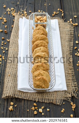 Peanut butter cookies, peanuts and a bottle of milk on a surface of dark natural wood covered with canvas fabric