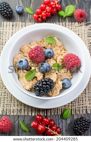 Whole grain cereal in a white bowl, fresh summer red currant berries), mint, a jar of soy milk on a white plate