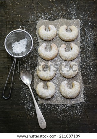 Sugar powdered vanilla crescents on a natural dark wood surface covered with baking paper