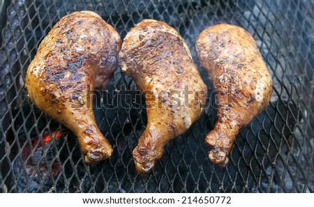 Chicken legs grilling over flames on a barbecue