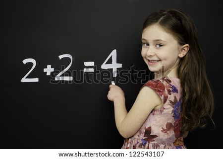 Smart young girl wearing a red dress writing math sums on a blackboard