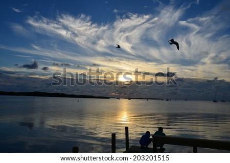 Sunset over the water in the Florida Keys, birds, people and clouds