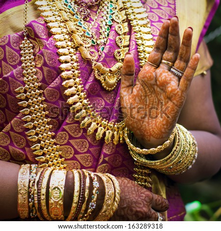 Hands of an Indian bride adorned with jewelery, bangles and painted with henna