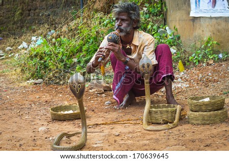 VARKALA, INDIA - JANUARY 9: snake charmer enchanting cobras in a street of Varkala, India, January 9, 2014. People practice this dangerous job as a way of begging charity