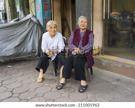 Hanoi, Vietnam - May 3, 2014: Portrait of two old women sitting on sidewalk of Hanoi street, Vietnam